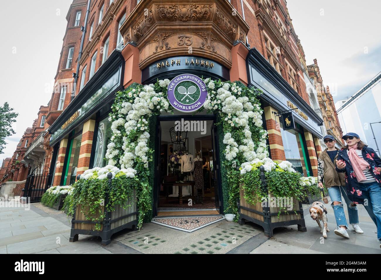 London, Großbritannien. 22. Juni 2021. Die Menschen passieren das Äußere des Ralph Lauren-Ladens am Sloane Square, der vor den kommenden Wimbledon-Tennismeisterschaften im All England Club dekoriert wurde. Ralph Lauren liefert den Beamten bei der Veranstaltung Outfits. Lockdown-Beschränkungen werden die Menge begrenzen, aber das Finale wird voll ausgelastet sein, wenn die Einschränkungen gelockert werden. Kredit: Stephen Chung / Alamy Live Nachrichten Stockfoto