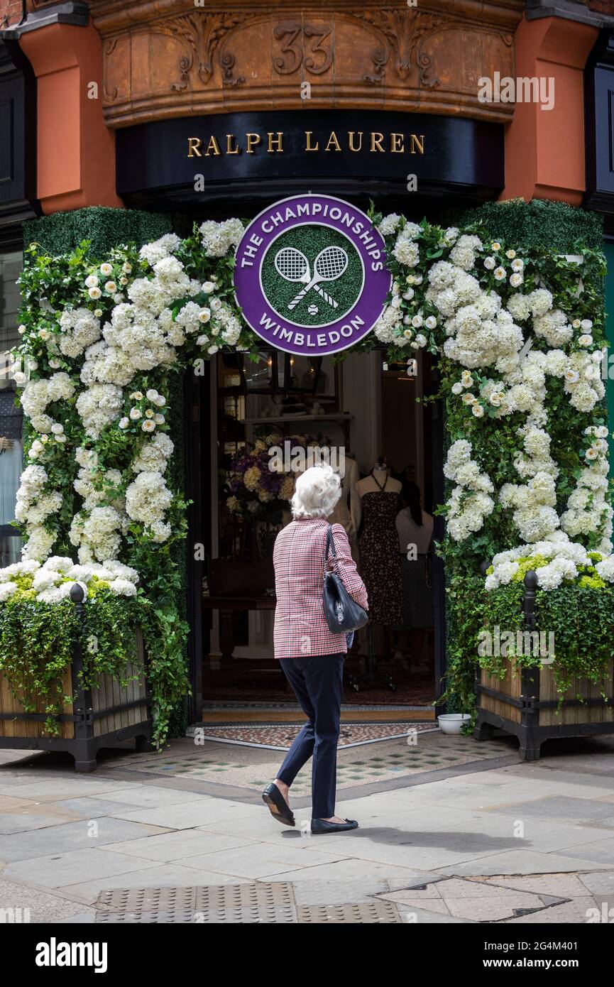 London, Großbritannien. 22. Juni 2021. Eine Frau geht an der Außenfassade des Ralph Lauren-Ladens am Sloane Square vorbei, der vor den kommenden Wimbledon-Tennismeisterschaften im All England Club dekoriert wurde. Ralph Lauren liefert den Beamten bei der Veranstaltung Outfits. Lockdown-Beschränkungen werden die Menge begrenzen, aber das Finale wird voll ausgelastet sein, wenn die Einschränkungen gelockert werden. Kredit: Stephen Chung / Alamy Live Nachrichten Stockfoto