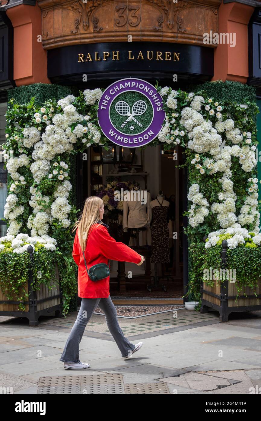 London, Großbritannien. 22. Juni 2021. Eine Frau geht an der Außenfassade des Ralph Lauren-Ladens am Sloane Square vorbei, der vor den kommenden Wimbledon-Tennismeisterschaften im All England Club dekoriert wurde. Ralph Lauren liefert den Beamten bei der Veranstaltung Outfits. Lockdown-Beschränkungen werden die Menge begrenzen, aber das Finale wird voll ausgelastet sein, wenn die Einschränkungen gelockert werden. Kredit: Stephen Chung / Alamy Live Nachrichten Stockfoto