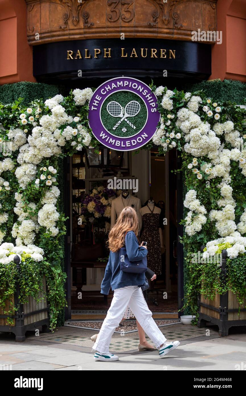 London, Großbritannien. 22. Juni 2021. Eine Frau geht an der Außenfassade des Ralph Lauren-Ladens am Sloane Square vorbei, der vor den kommenden Wimbledon-Tennismeisterschaften im All England Club dekoriert wurde. Ralph Lauren liefert den Beamten bei der Veranstaltung Outfits. Lockdown-Beschränkungen werden die Menge begrenzen, aber das Finale wird voll ausgelastet sein, wenn die Einschränkungen gelockert werden. Kredit: Stephen Chung / Alamy Live Nachrichten Stockfoto