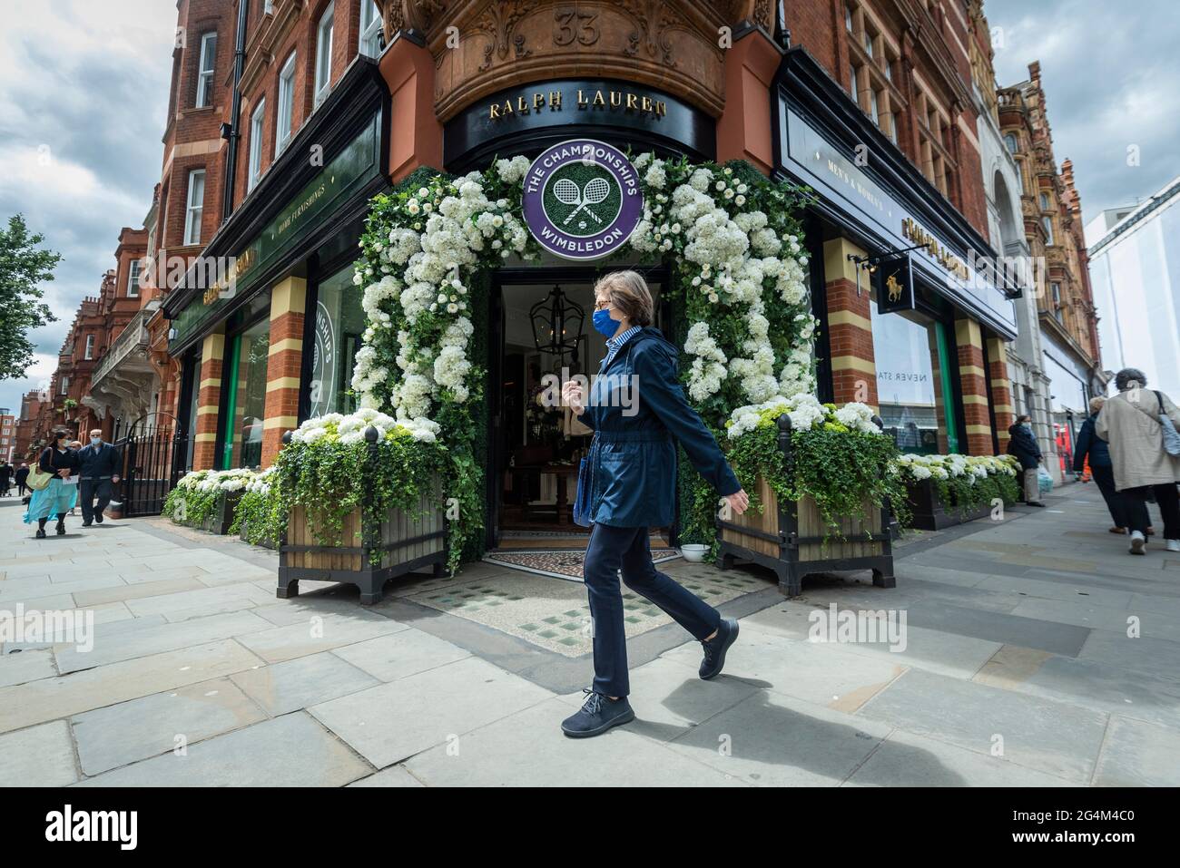 London, Großbritannien. 22. Juni 2021. Eine Frau geht an der Außenfassade des Ralph Lauren-Ladens am Sloane Square vorbei, der vor den kommenden Wimbledon-Tennismeisterschaften im All England Club dekoriert wurde. Ralph Lauren liefert den Beamten bei der Veranstaltung Outfits. Lockdown-Beschränkungen werden die Menge begrenzen, aber das Finale wird voll ausgelastet sein, wenn die Einschränkungen gelockert werden. Kredit: Stephen Chung / Alamy Live Nachrichten Stockfoto
