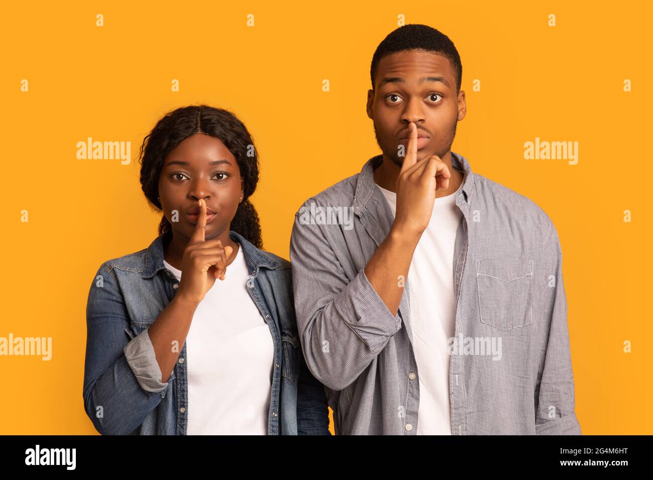 Sagen Sie kein Wort. Schwarzer Mann und Frau halten die Finger auf den Lippen Stockfoto