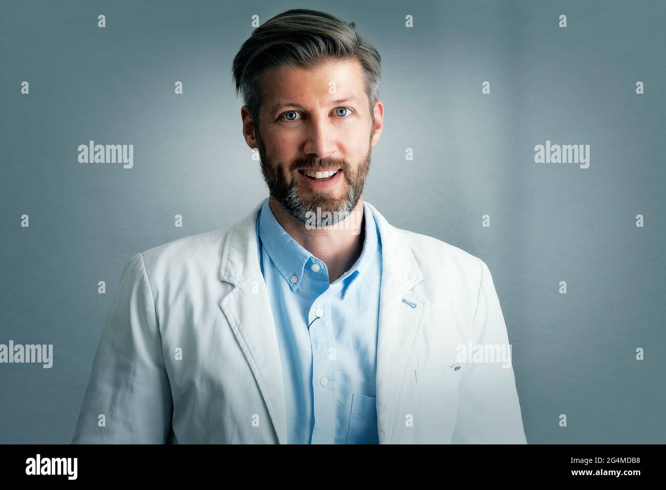 Porträt eines gutaussehenden Geschäftsmannes mittleren Alters, der Blazer und Hemd trägt, während er auf einem isolierten grauen Hintergrund steht. Speicherplatz kopieren. Stockfoto