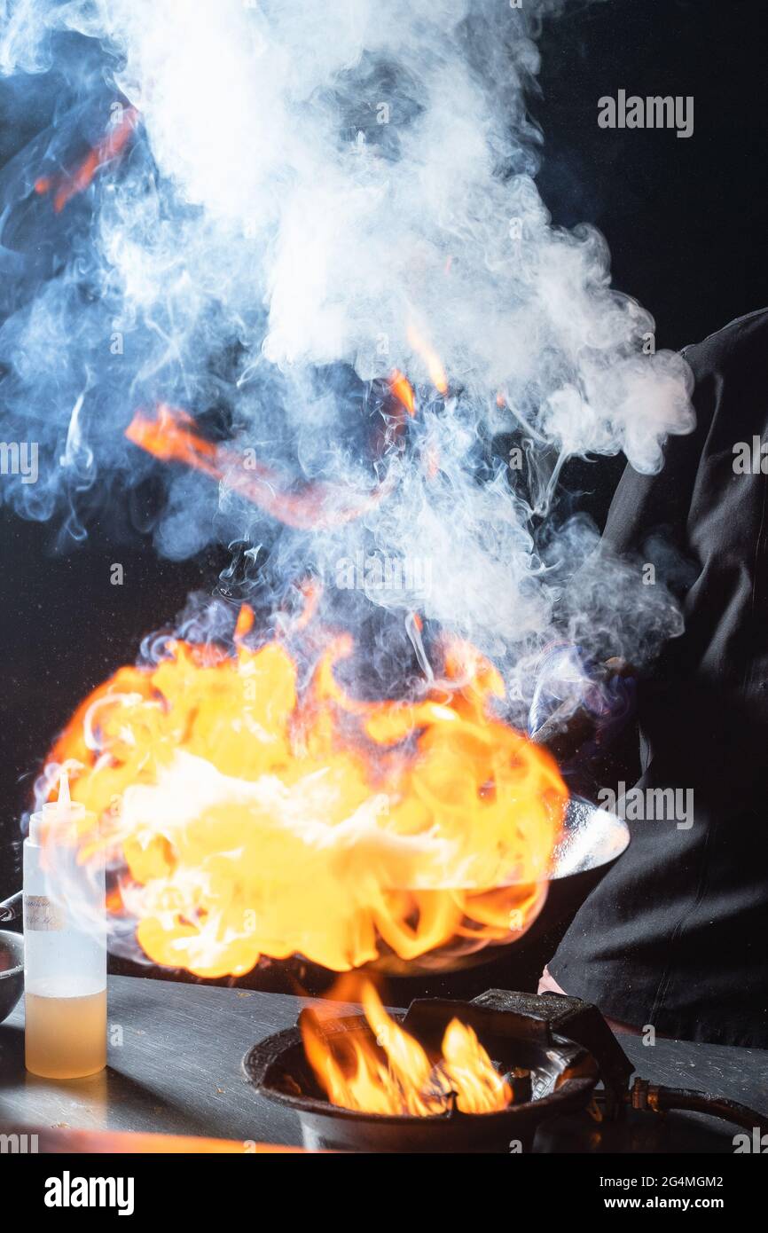 Flambe Bratpfanne Wok, Kochen auf Feuer. Panasiatische Küche. Street Food Stockfoto