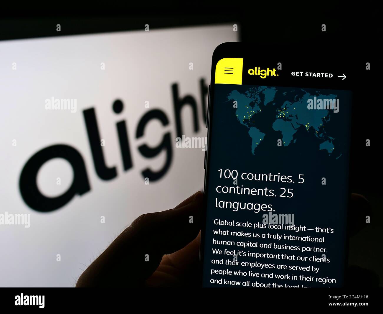Person, die Mobiltelefon mit der Webseite des US-amerikanischen Outsourcing-Unternehmens Alight Solutions LLC auf dem Bildschirm vor dem Logo hält. Konzentrieren Sie sich auf die Mitte des Telefondisplays. Stockfoto