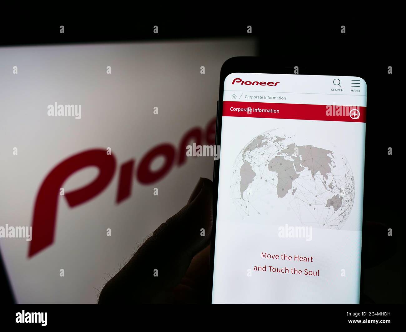 Person, die Mobiltelefon mit Website des japanischen Elektronikunternehmens Pioneer K.K. auf dem Bildschirm vor dem Logo hält. Konzentrieren Sie sich auf die Mitte des Telefondisplays. Stockfoto