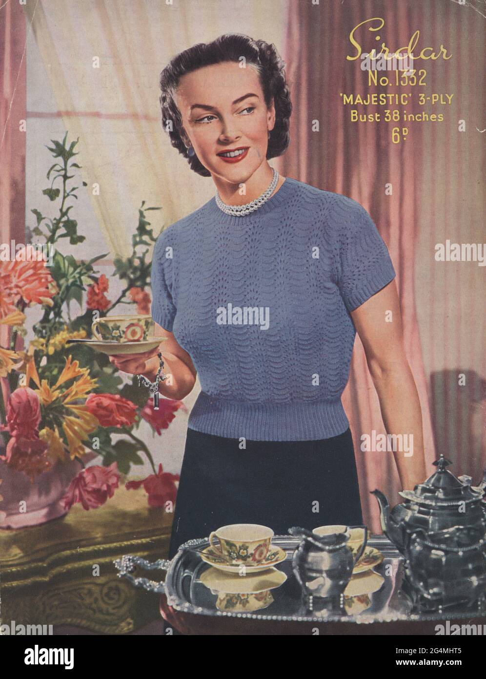 Im Vorderteil mit Vintage-Strickmuster. Ende der 1940er Jahre. Damen Kurzarm-Pullover. Britisch. Tee-Service aus Porzellan und versilbertem Tee auf dem Tisch, großer Blumenstrauß in Vase, vorstädtisches Wohnzimmer. Stockfoto