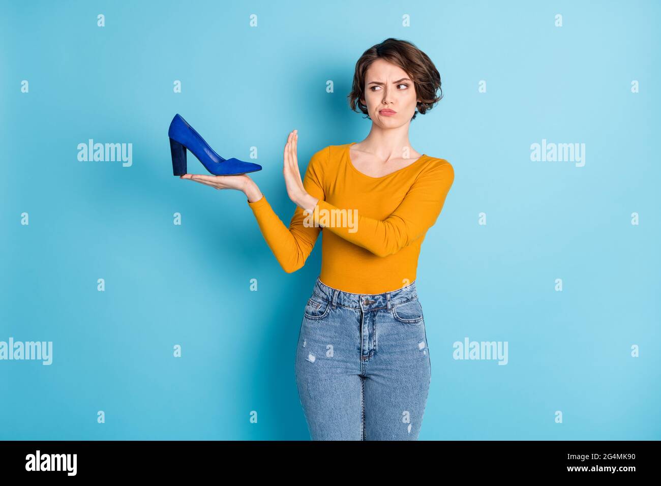 Foto von traurig schön brünette kurze Frisur Dame verweigern Schuhe tragen braunes Hemd isoliert auf hellblauen Hintergrund Stockfoto