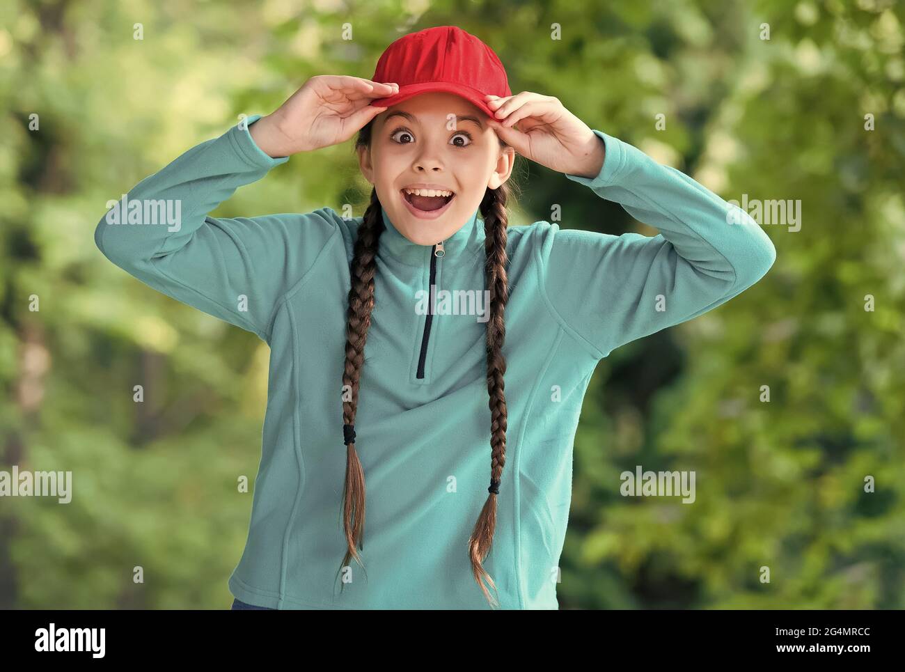 Überrascht Mädchen halten Mund Augen weit offen Befestigung stilvolle Kappe mit Mode-Look in lässigen Stil natürliche Landschaft, Hipster Stockfoto