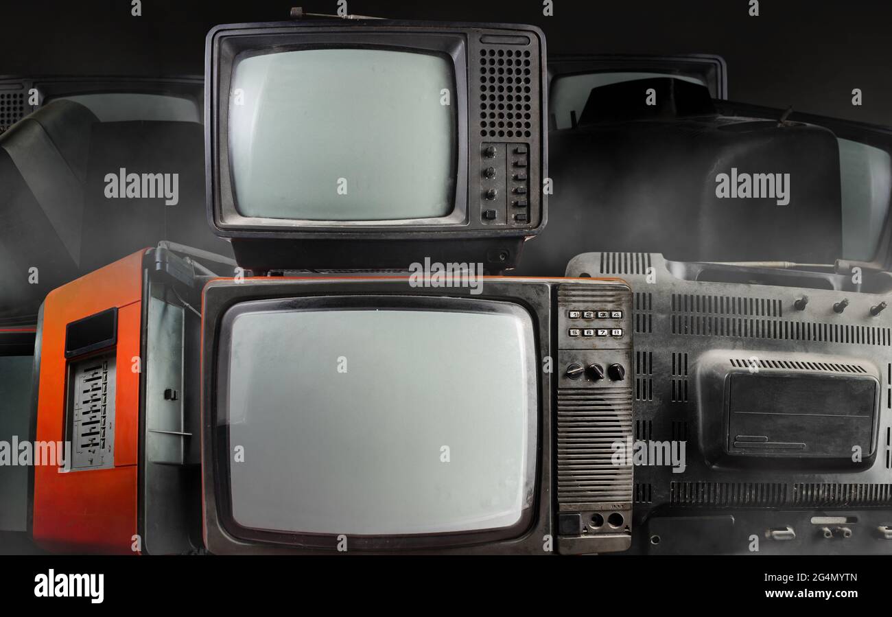 Foto von altmodischen fernsehern auf dunklem, nebligen Hintergrund gestapelt. Stockfoto