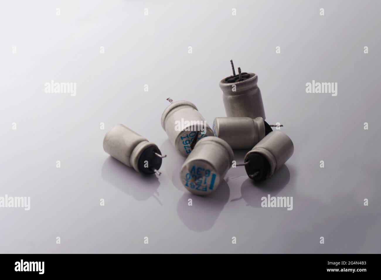 Beschädigter gesprungener elektrolytisch aufgeblähter Explosionskondensator auf weißem Hintergrund. Minimales Reparaturkonzept für die elektonische Technologie. Stockfoto