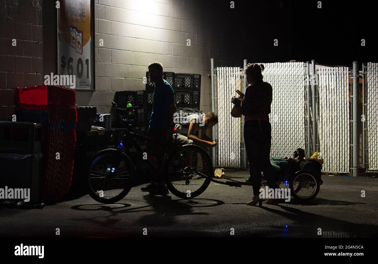 Zephyrhills, Florida, USA. Juni 2021. Eine junge obdachlose Frau trifft sich zu Freunden und sucht einen Schlafplatz für die Nacht in einer kleinen Stadt in Zentral-Florida. Ein Wagen, der an einem Fahrrad befestigt ist, schleppt ihre Besitztümer. Lokale Fürsprecher der Obdachlosen sind besorgt über den wachsenden Drogenkonsum, der zur zunehmenden Obdachlosenkrise beiträgt. Quelle: Robin Rayne/ZUMA Wire/Alamy Live News Stockfoto