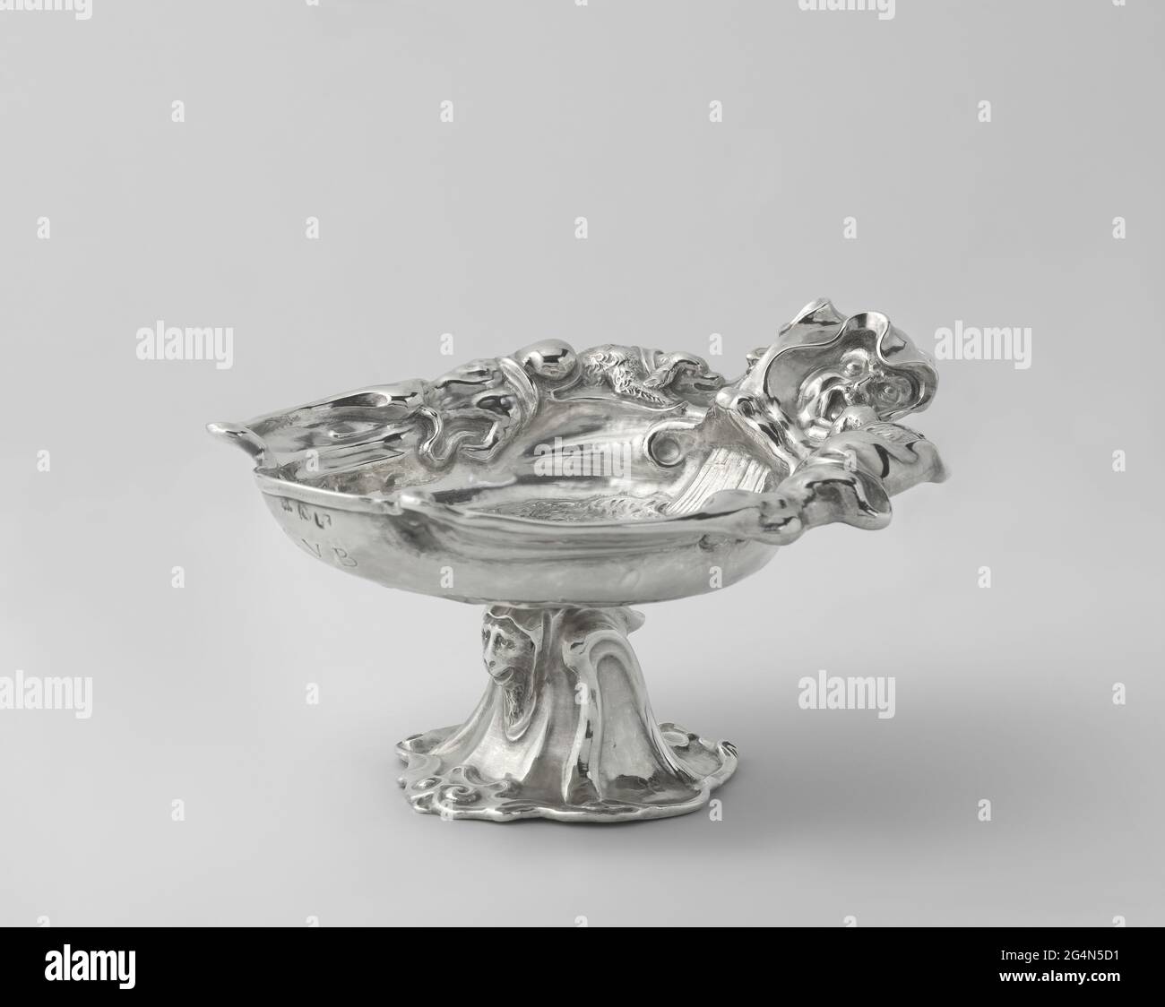 Trinkbecher mit Narrenköpfen. Diese Tasse ist am besten von oben betrachtet. Der fast symmetrische Rand besteht aus zwei Narrenköpfen. Ihre Hauben erstrecken sich auf beiden Seiten auf einen Rand, der zwei kleine Hunde umhüllt und dann in das aurikuläre (weiche, fleischige, labenartige) Ornament mündet, das das Markenzeichen der Van Vianen Familie ist. Unter den Köpfen der Narren fließt ein Wasserstrom in die Schale, in der ein Delphin und andere Meerestiere schwimmen. Stockfoto