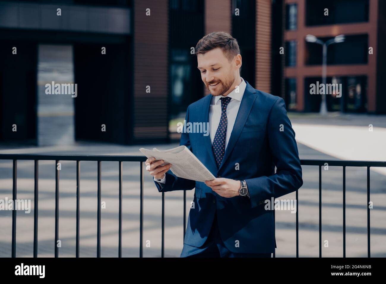 Trendy gekleideter Geschäftsmann in stilvoller Kleidung, der im Freien Geschäftsnachrichten liest Stockfoto