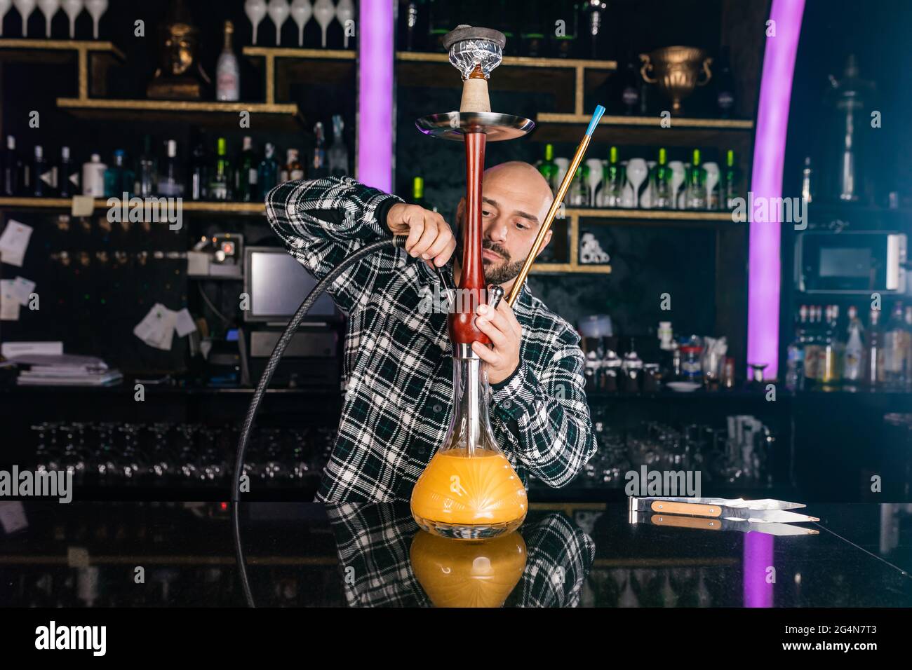 Mann, der in einem Nachtclub traditionelle Shisha zubereitete Stockfoto