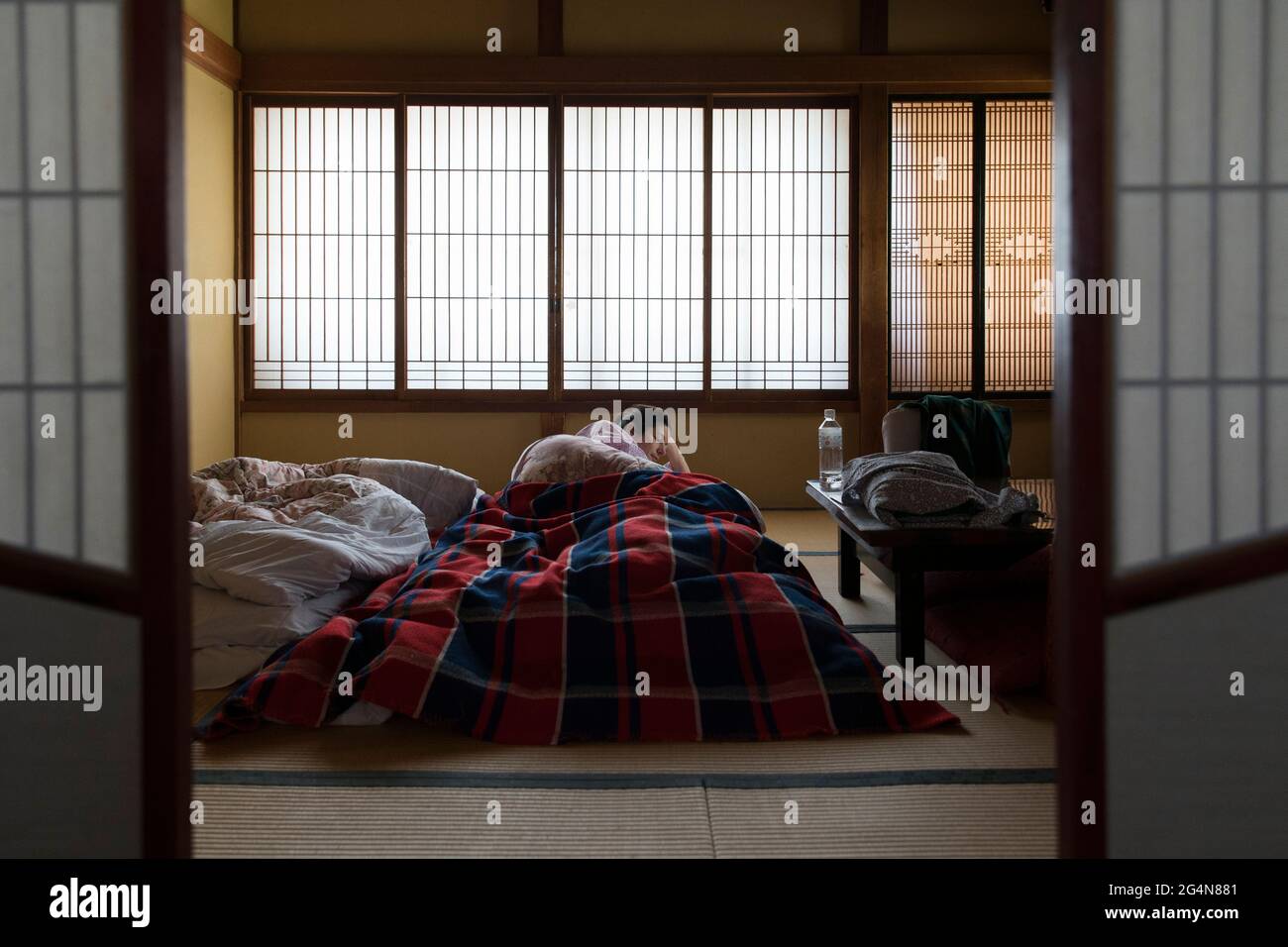 Ein Tourist, der sich in einem traditionellen Tatami-Zimmer in Japan entspannt Stockfoto