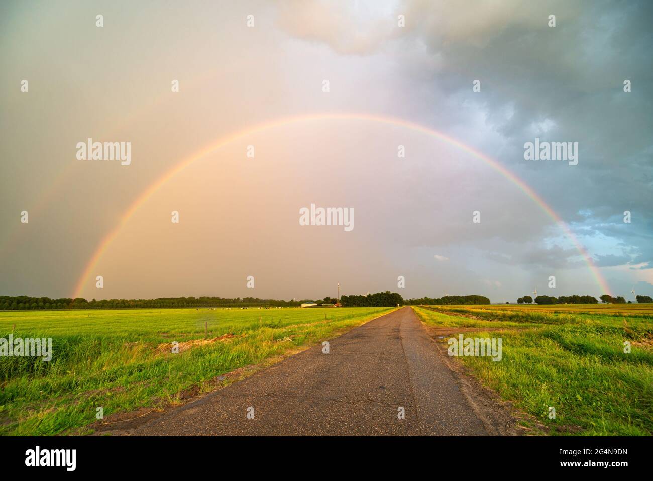Heller doppelter Regenbogen über einer Landstraße am Ende des Tages Stockfoto