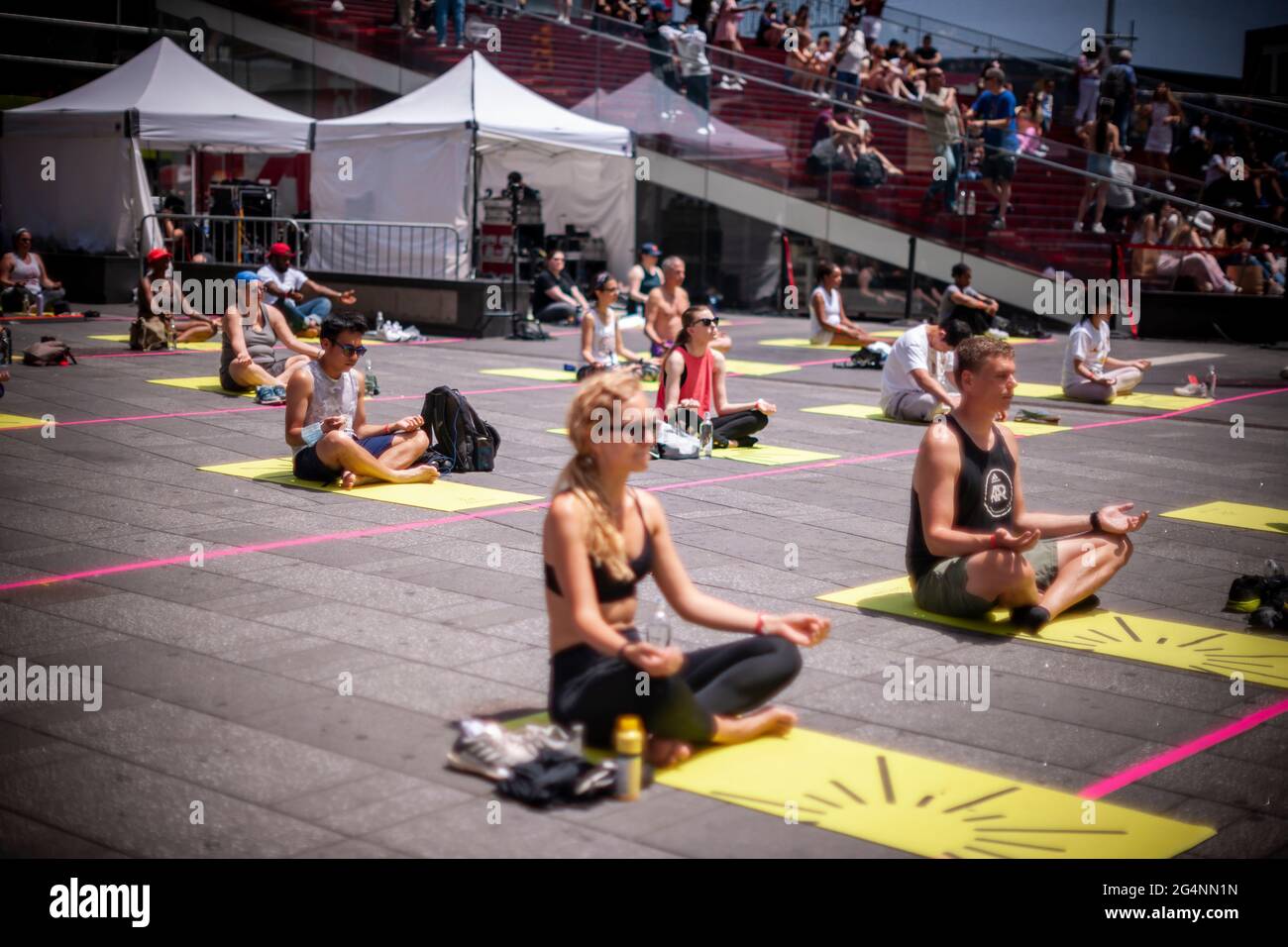 Sozial ferne Yogapraktiker packen den Times Square in New York ein, um am ersten Sommertag, Sonntag, 21. Juni 2021, Yoga zu praktizieren. Die jährliche Sonnenwende am Times Square, „Mind over Madness“, gesponsert von Ayrie, dem Generalkonsulat von Indien, New York und SmartWater, dehnt die Fähigkeit der Yogis aus, den Lärm und das visuelle Durcheinander, das sie an der Kreuzung der Welt umgibt, zu blockieren. Der erste Sommertag wurde von den Vereinten Nationen zum Internationalen Tag des Yoga erklärt. (© Richard B. Levine) Stockfoto