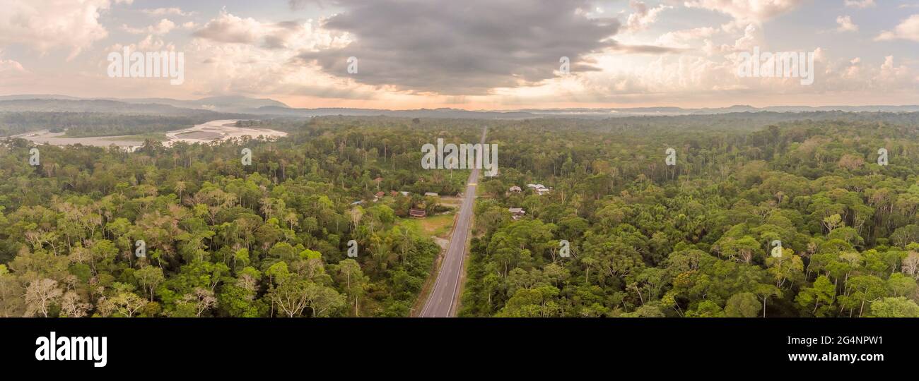 Luftaufnahme einer geraden Amazonas-Straße in Ecuador mit Rio Napo und dem Galeras-Berg im Hintergrund und Gewitterwolken. Straßen bringen Doppelpunkt Stockfoto