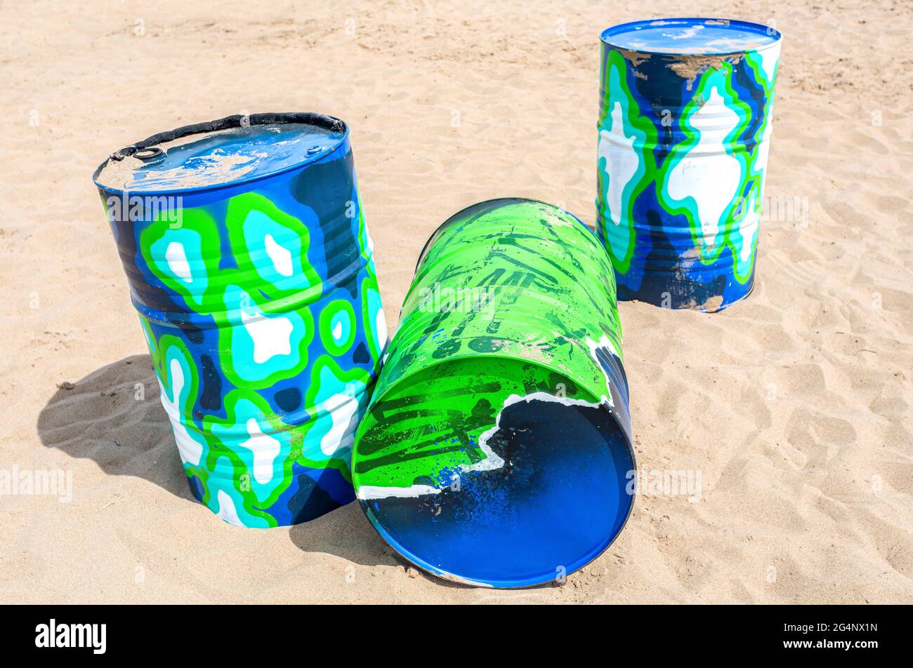 Samara, Russland - 14. Juni 2021: An einem sonnigen Tag liegen lackierte Metallfässer auf dem Sand. Fässer sind in verschiedenen Farben lackiert Stockfoto