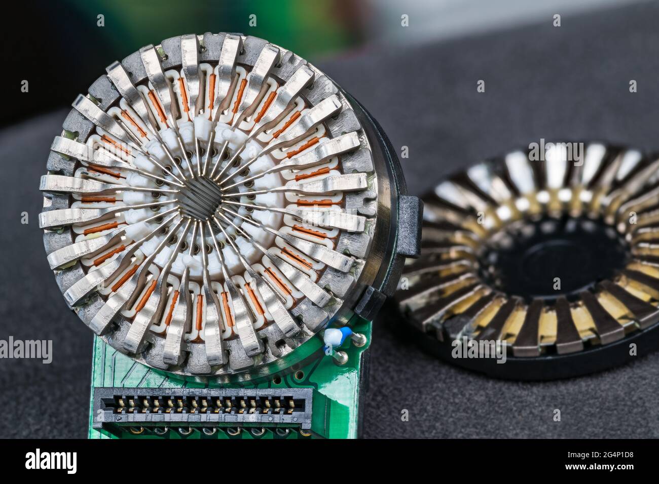 Nahaufnahme von Nadeldruckerkopf und Steckverbinder in grüner Leiterplatte, grauer Hintergrund. Induktivitäten in einem runden 24-poligen Teil der Computerdruckmaschine. Stockfoto