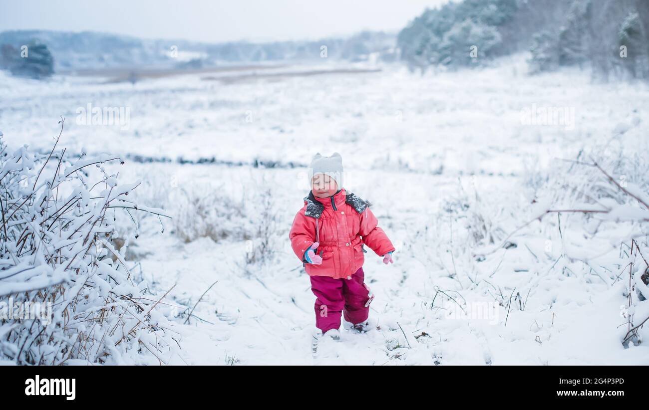 Kleines Mädchen wirft Schneeball. Kind spielt im Winter draußen im Schnee. Stockfoto