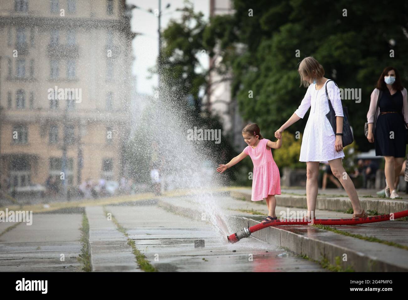 Warschau, Polen. Juni 2021. Ein Mädchen kühlt sich ab, indem es am 22. Juni 2021 in Warschau, Polen, mit einem Wasserspray spielt, das gegen die Hitzewelle eingesetzt wurde. Eine Hitzewelle traf Polen, wo die höchsten Temperaturen doppelt so hoch waren wie der historische Durchschnitt in einigen Teilen des Landes. Quelle: Jaap Arriens/Xinhua/Alamy Live News Stockfoto