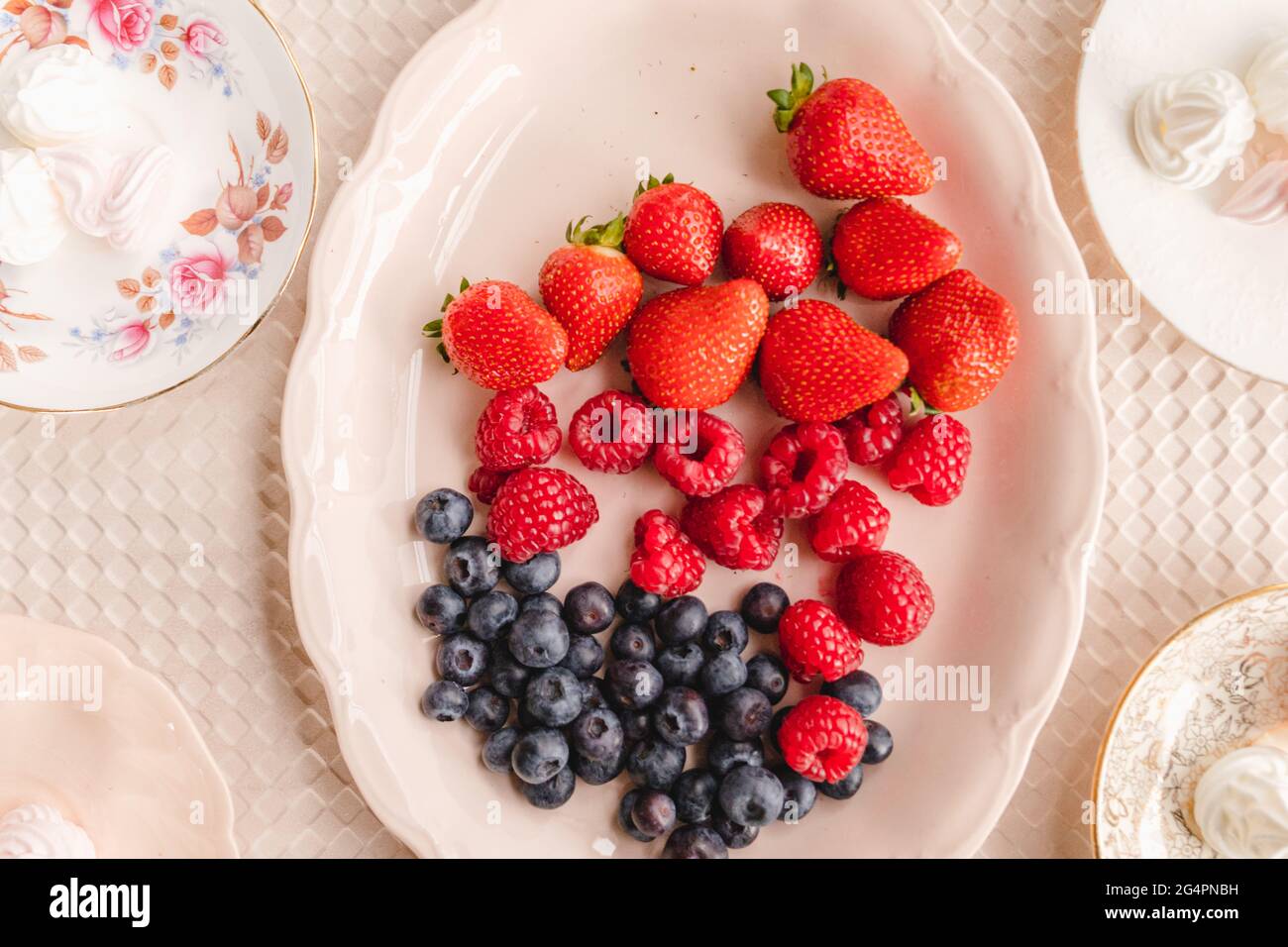 Leichte und helle Teller mit Baiser mit saisonalen Beeren, Erdbeeren, Himbeeren und Blaubeeren Stockfoto