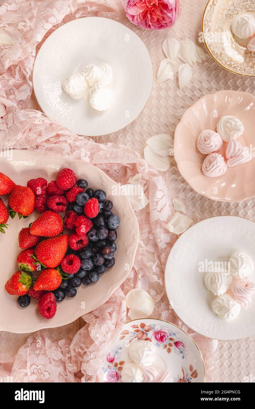 Leichte und helle Teller mit Baiser mit saisonalen Beeren, Erdbeeren, Himbeeren und Blaubeeren Stockfoto