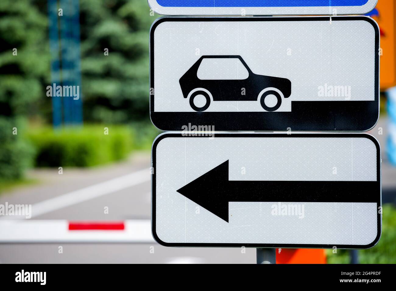 Straßenschild Parkplatz für Autos und ein Pfeil der Bewegungsrichtung auf dem Hintergrund einer Barriere. Stockfoto