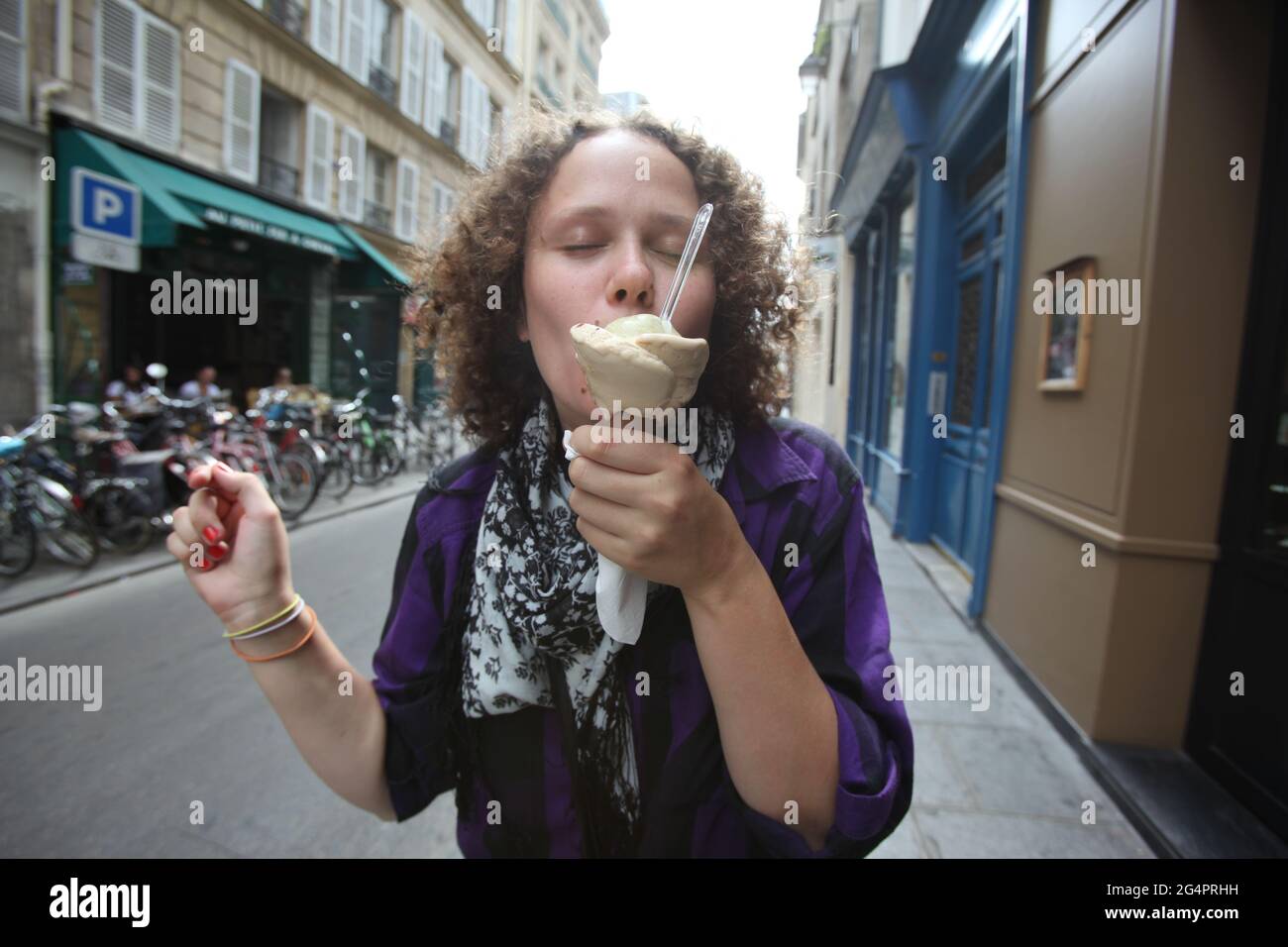 Verträumte weibliche Eisspezier, die im Sommer in der City Street leckeres Eis mit geschlossenen Augen essen Stockfoto
