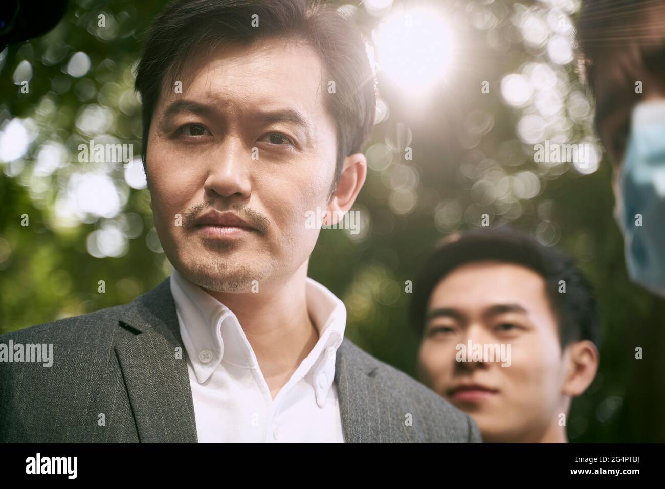asiatischer Geschäftsmann, der mit einem lustigen Gesichtsausdruck auf die Kamera schaut Stockfoto