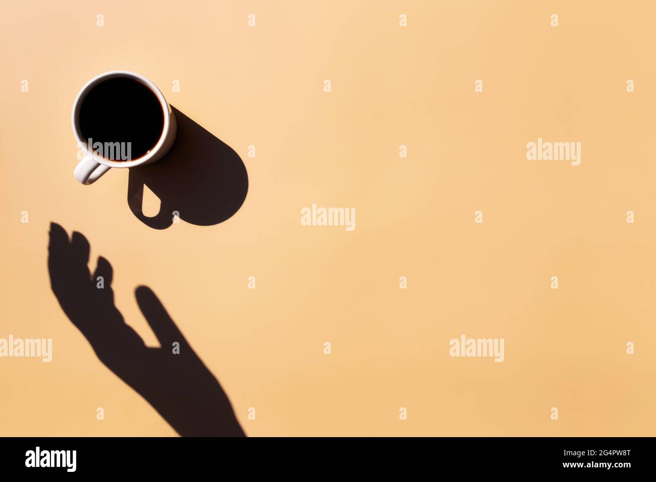 Weiße Tasse und Untertasse Teller aus schwarzem Espresso Kaffee von oben mit Schatten der Sonne und Hand halten oder berühren Sie die Tasse auf gelb beige Terrakotta b Stockfoto