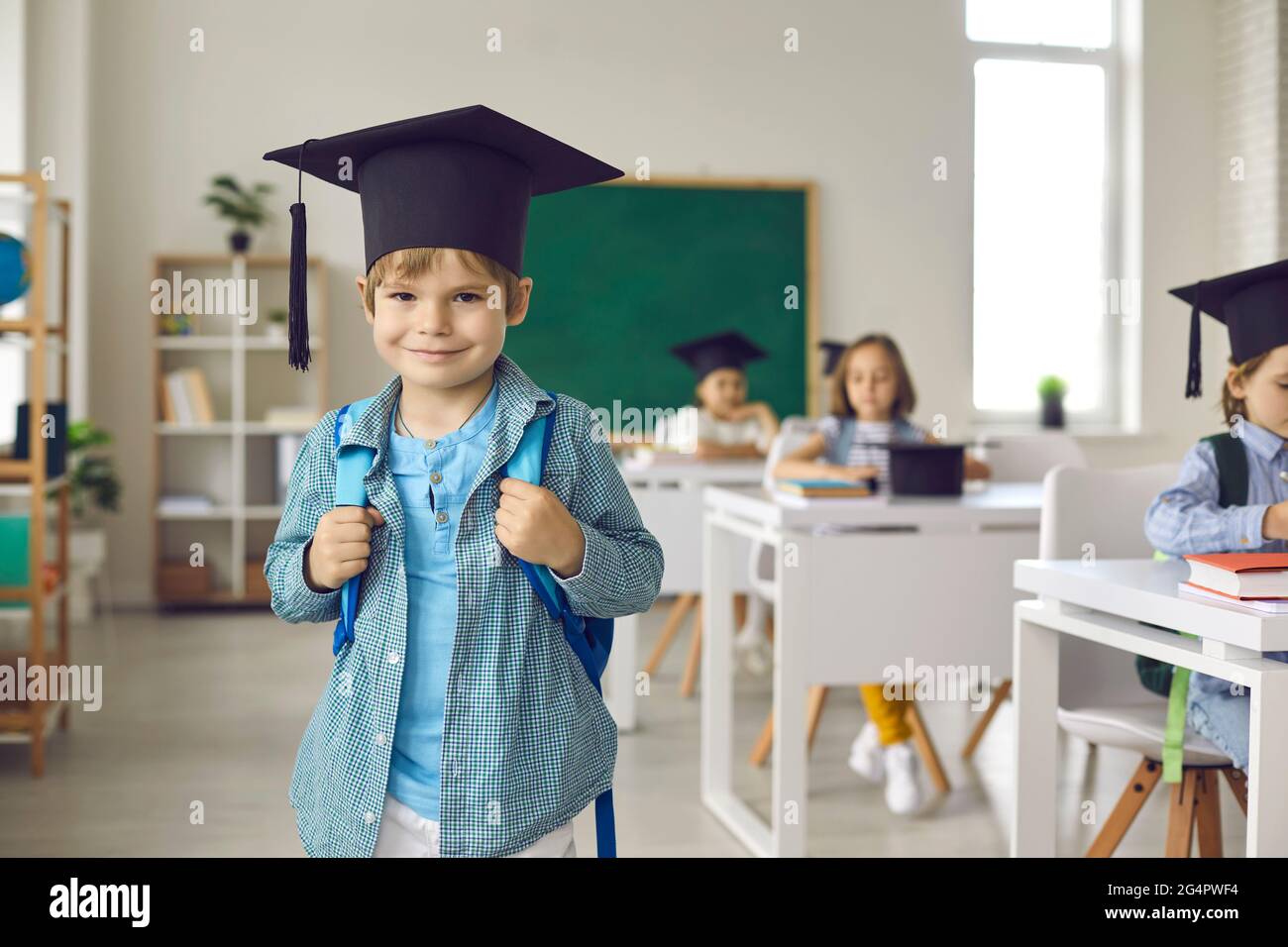 Porträt eines glücklichen Grundschulabsolventen in akademischem Hut im Klassenzimmer Stockfoto