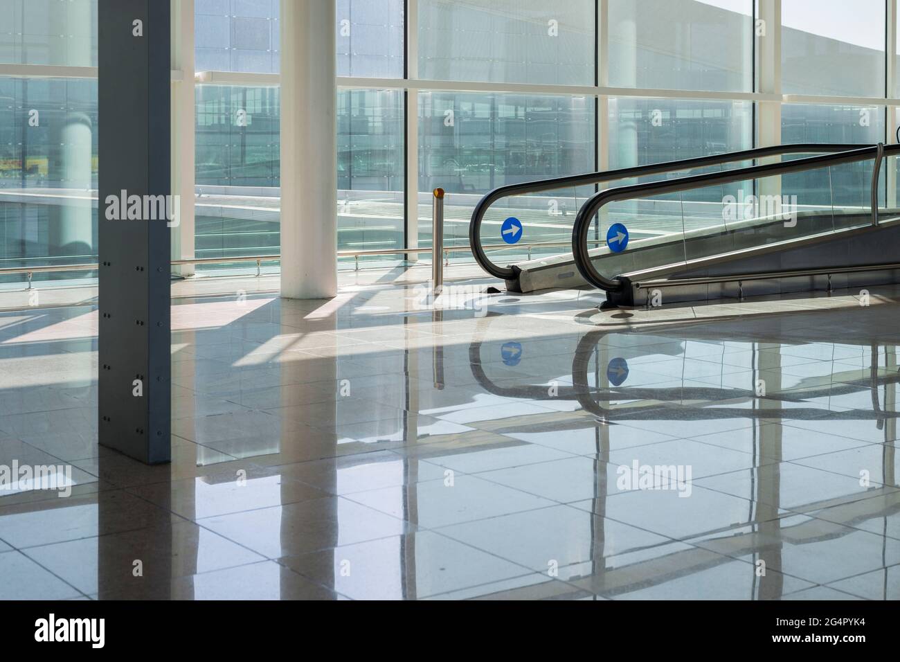 Helle Flughafenhalle mit breiten Fenstern und leerem Travelator Stockfoto