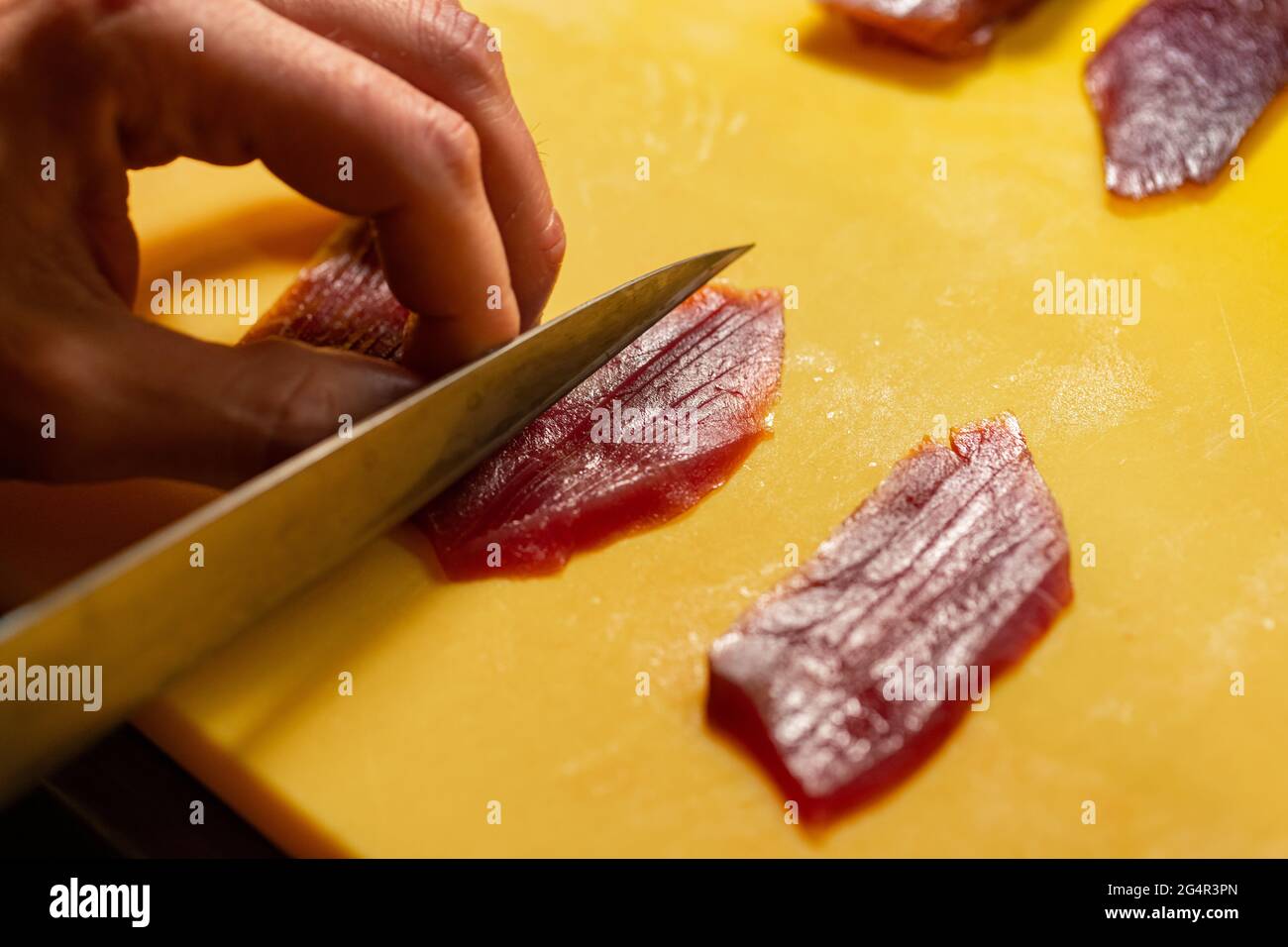 Der Sushi-Koch hat an der Sushi-Bar frischen Thunfisch in Scheiben geschnitten. Stockfoto