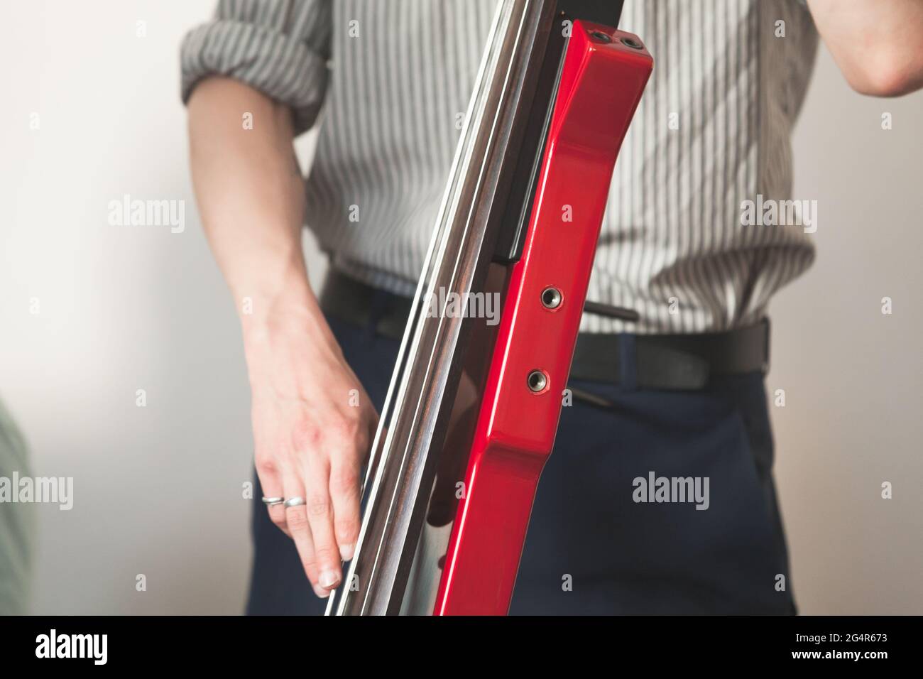Hände eines Mannes, der roten elektrischen Kontrabass spielt. Nahaufnahme mit selektivem Fokus. Live-Musik im Hintergrund Stockfoto