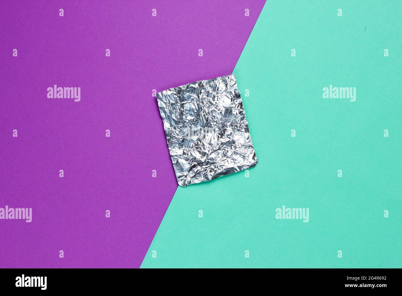 Ein Stück Folie auf farbigem Papierhintergrund. Draufsicht. Minimalismus-Konzept Stockfoto