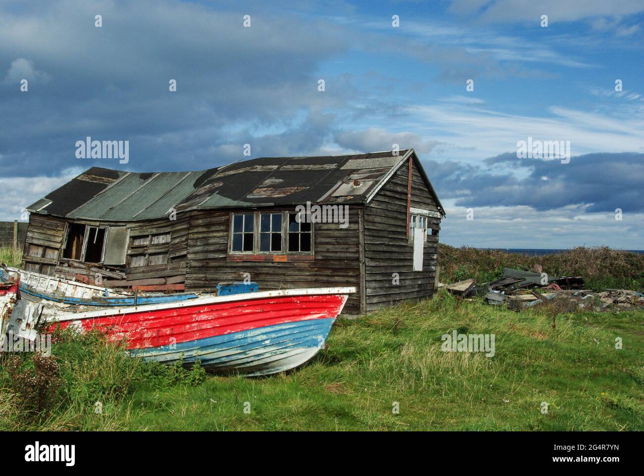 Alte Fischerboote neben einem baufälligen Holzschuppen am Ufer in Beadnell, Northumberland, Großbritannien Stockfoto