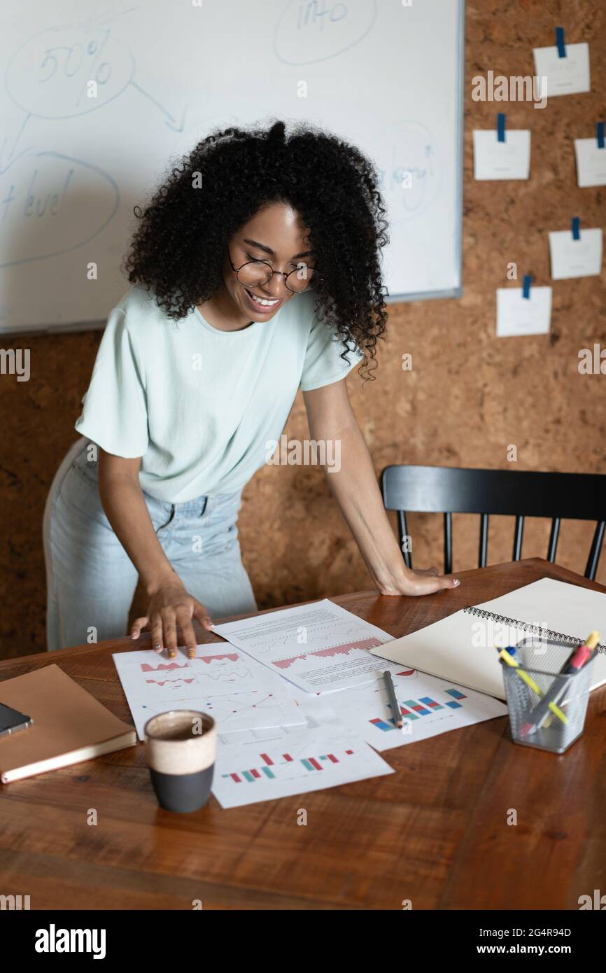 Eine schöne Geschäftsfrau, die mit Papieren arbeitet und im modernen Büro steht Stockfoto