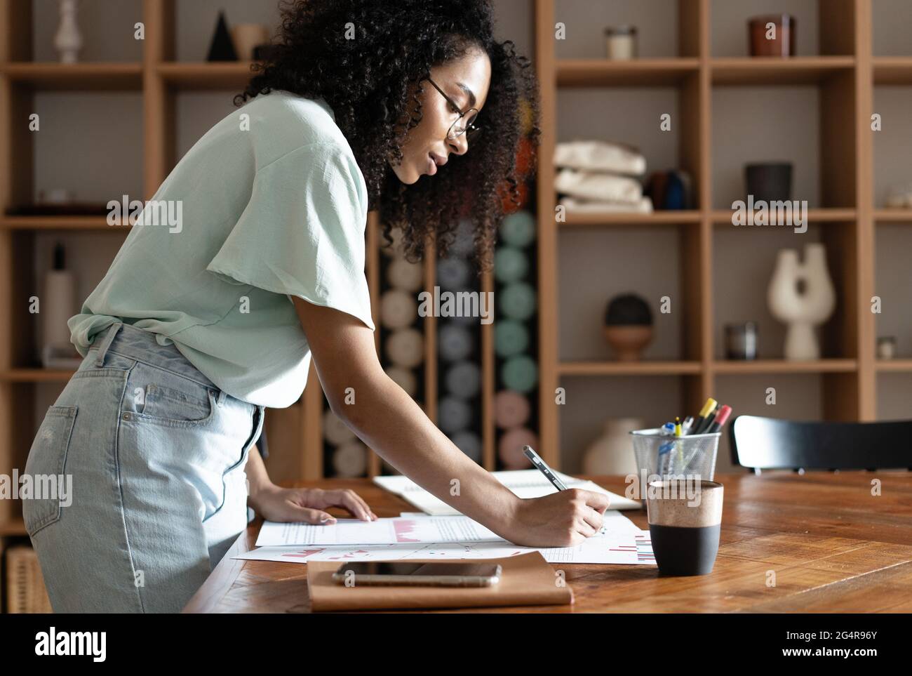 Eine schöne Geschäftsfrau, die mit Papieren arbeitet und im modernen Büro steht Stockfoto