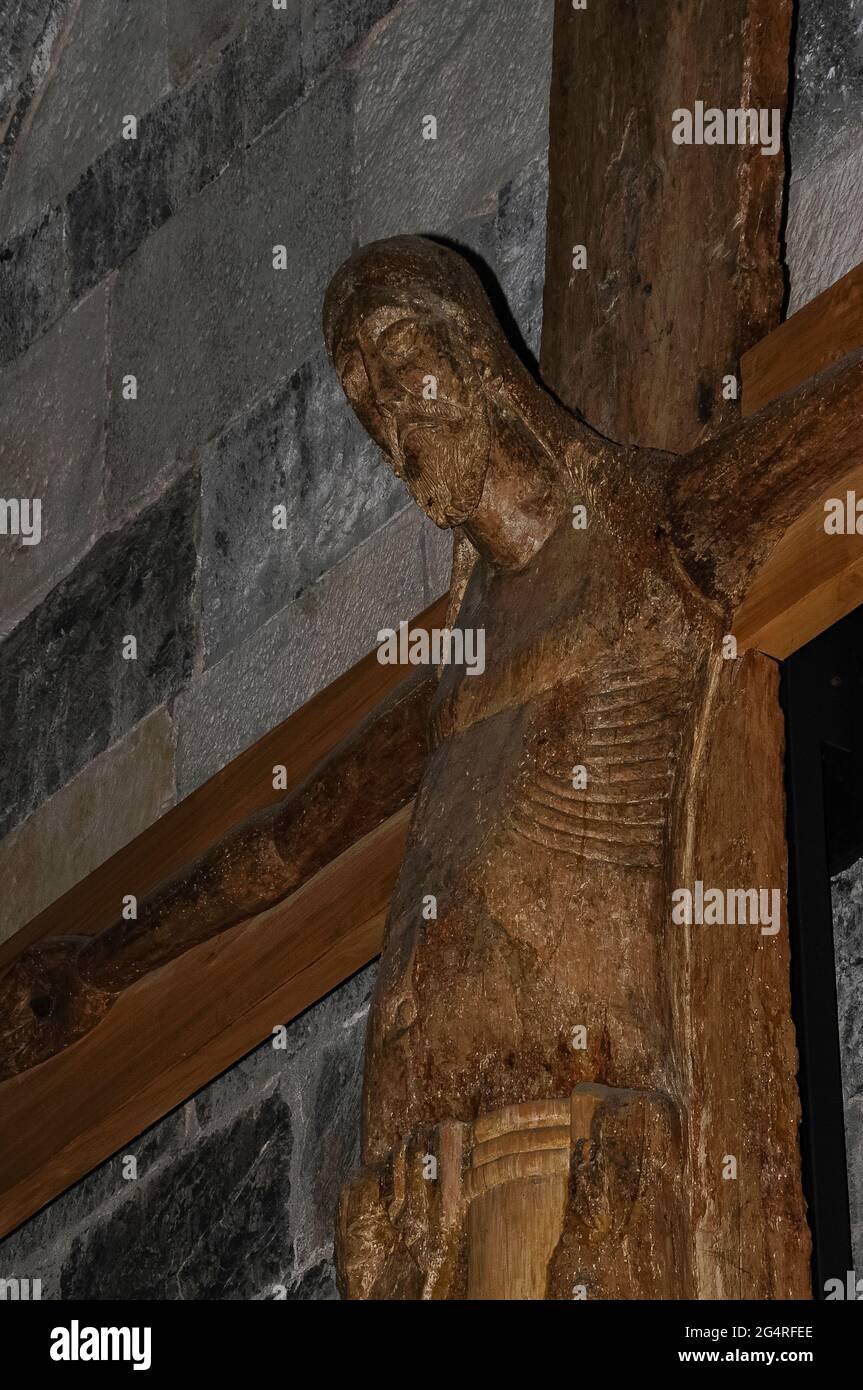 Dieses Meisterwerk mittelalterlicher religiöser Skulptur, ein Kruzifix, das Mitte des 11. Jahrhunderts aus einem soliden Pappelbaum geschnitzt wurde, mit den Armen aus Erlenholz, hängt jetzt in der Chiesa di Santa Maria del Tiglio, einem romanischen ehemaligen Taufbecken am Ufer des Comer Sees in Gravedona, Lombardei, Italien. Es mag zwar lombardischer Art sein, ist aber eher typisch für die französische oder deutsche Skulptur und ein ähnliches Kruzifix in Bronze ist im Benediktinerkloster Werden bei Essen im Ruhrgebiet erhalten. Stockfoto