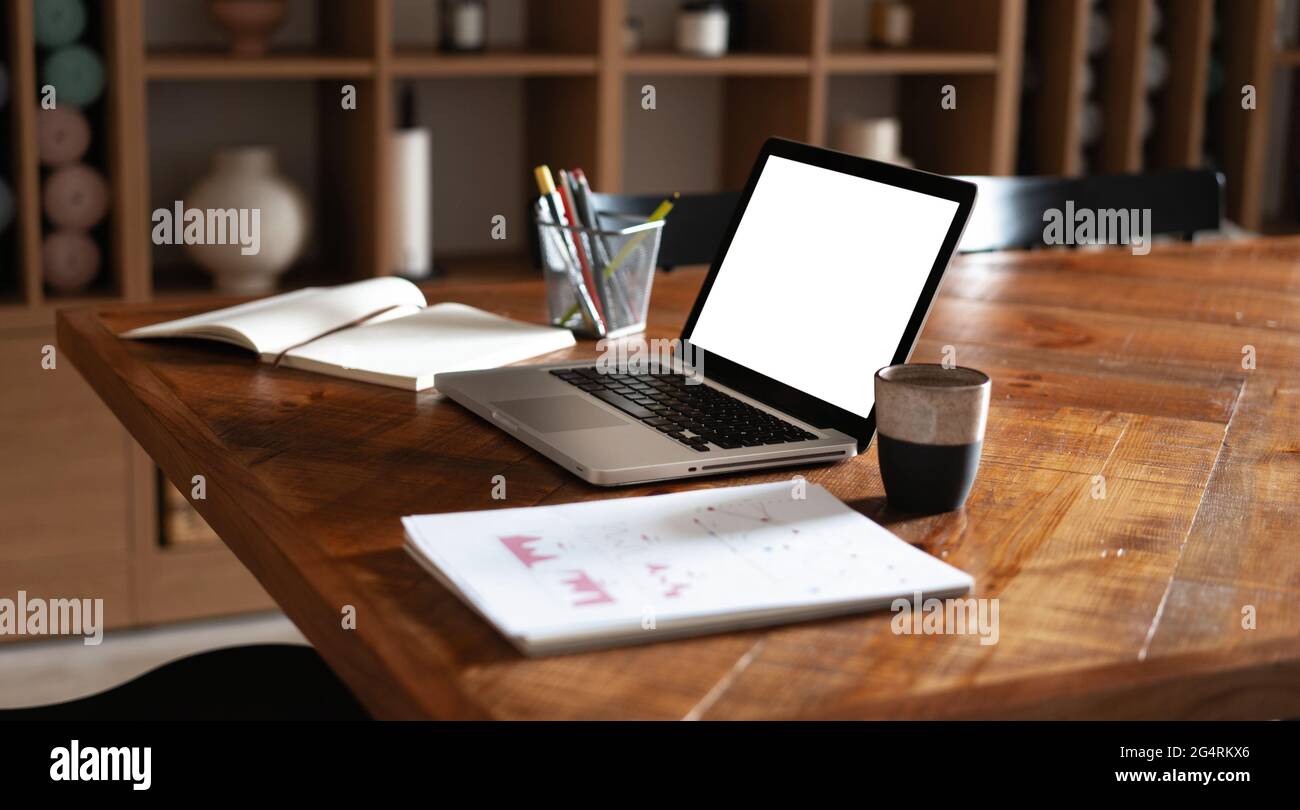 Moderner kreativer Arbeitsplatz mit Laptop-Notebook, weißer leerer Bildschirm auf dem Schreibtisch im Büroraum Stockfoto