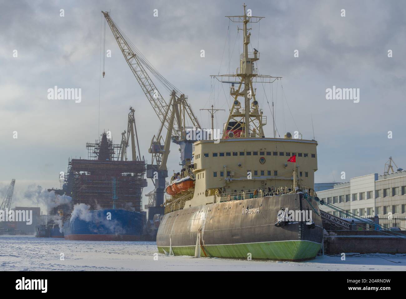 ST. PETERSBURG, RUSSLAND - 15. FEBRUAR 2021: Der alte Eisbrecher Krasin vor dem Hintergrund der Baltic Shipyard an einem frostigen Februartag Stockfoto