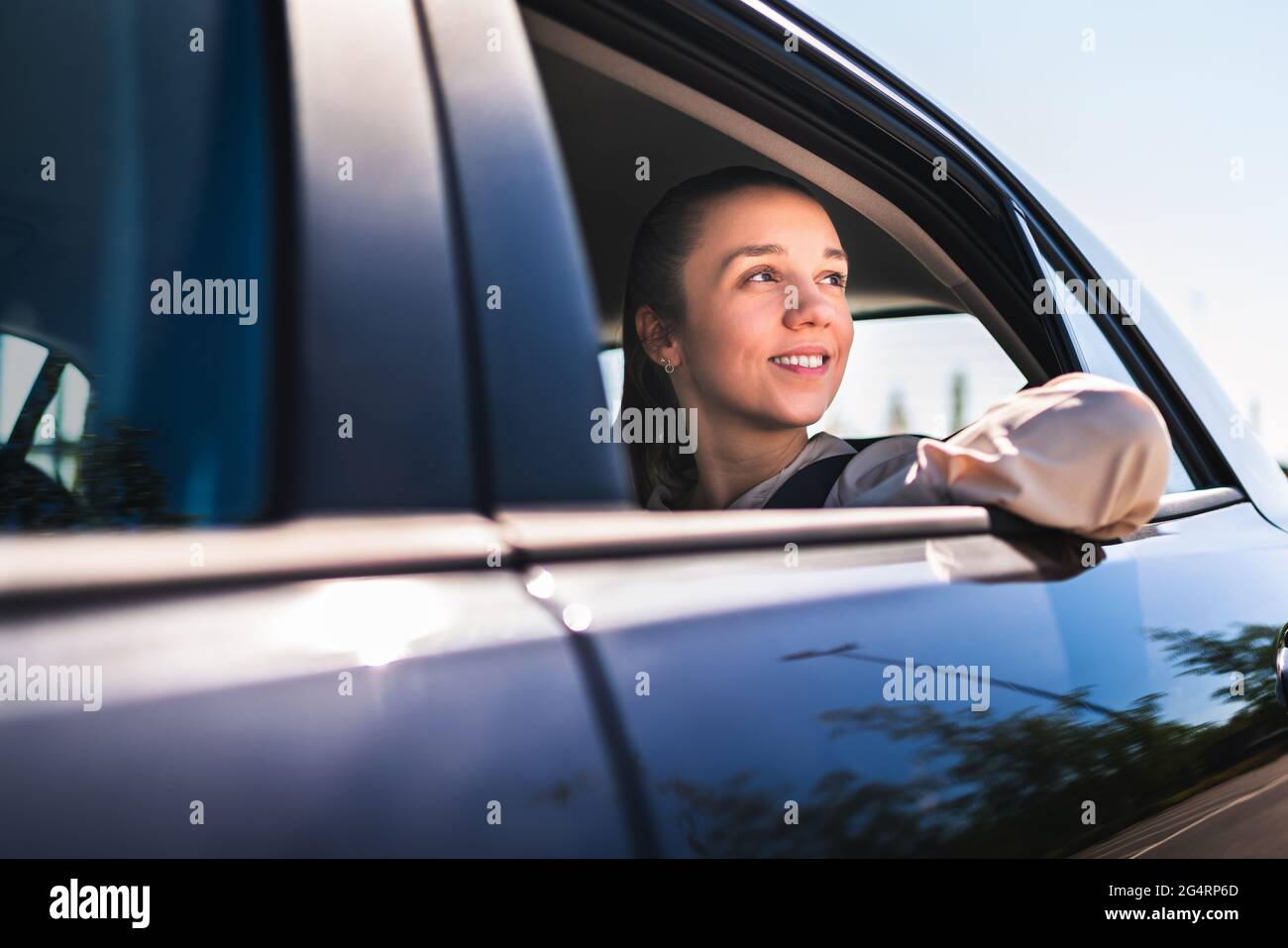 Passagier im Taxi oder Frau im Auto, die auf dem Rücksitz sitzt und vor dem Fenster schaut. Glückliche Kundin im Taxi. Elegante lächelnde Geschäftsfrau. Stockfoto