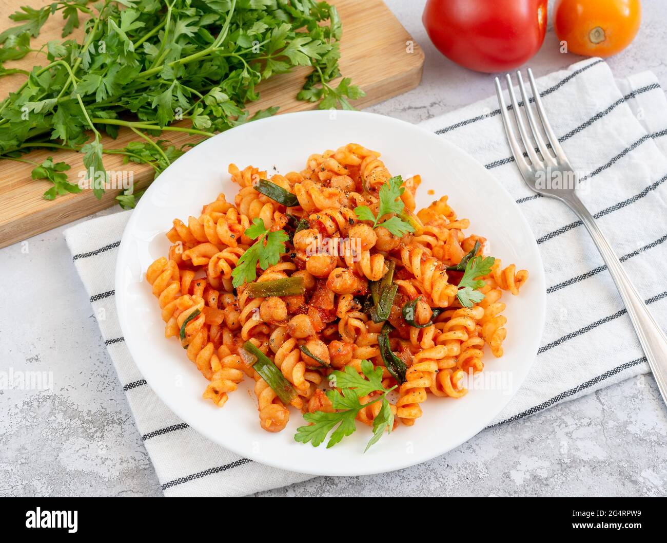 Fusilli-Pasta mit Kichererbsen und Tomaten- und Kräutersoße auf einem Servierteller Stockfoto