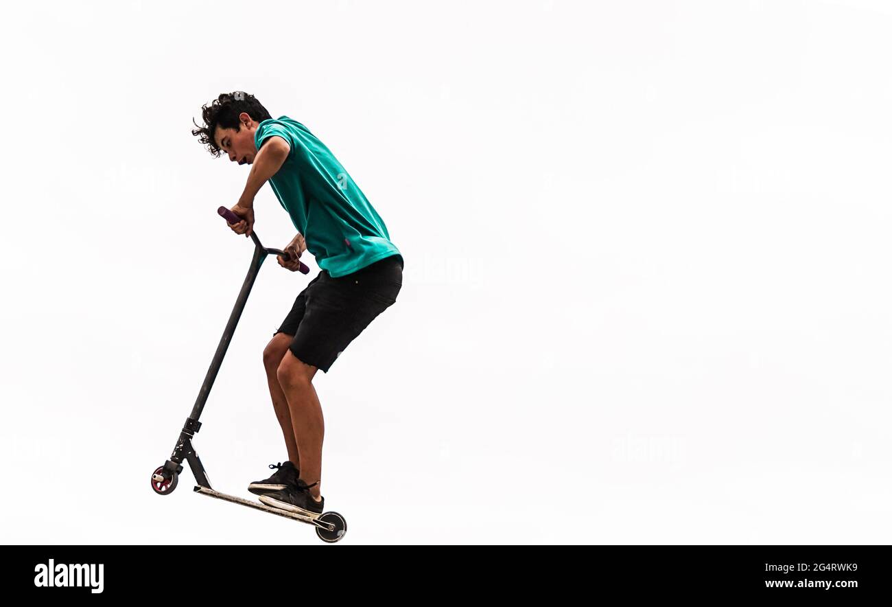 Wütender kleiner Junge mit seinem Roller. Junge auf Roller kippt in die Luft. Weißer Hintergrund und Kopierbereich. Extremes Sportkonzept. Stockfoto