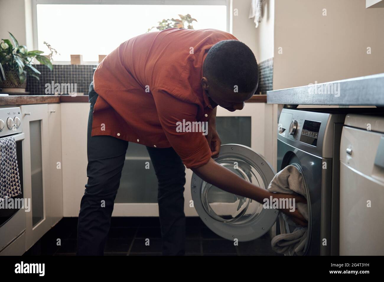 Junger afrikanischer Mann, der in seiner Küche Kleidung wäscht Stockfoto