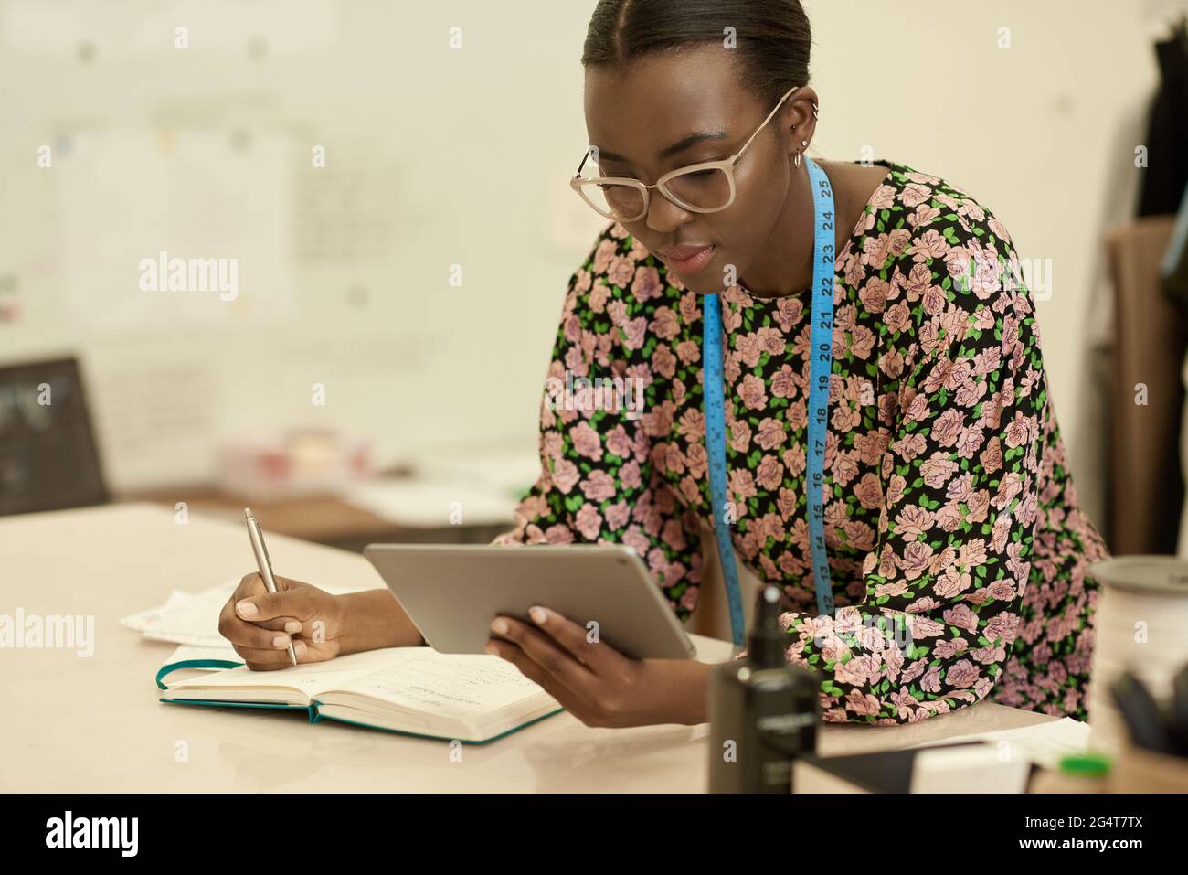 Afrikanische Designerin für Kleidung, die in ihrem Studio ein Tablet benutzt Stockfoto