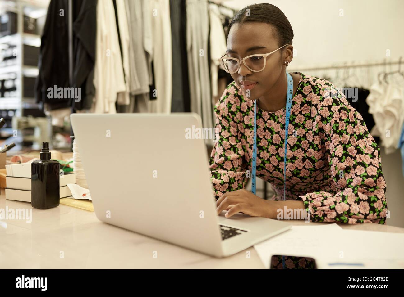 Afrikanische Designerin für Kleidung, die in ihrem Studio am Laptop arbeitet Stockfoto